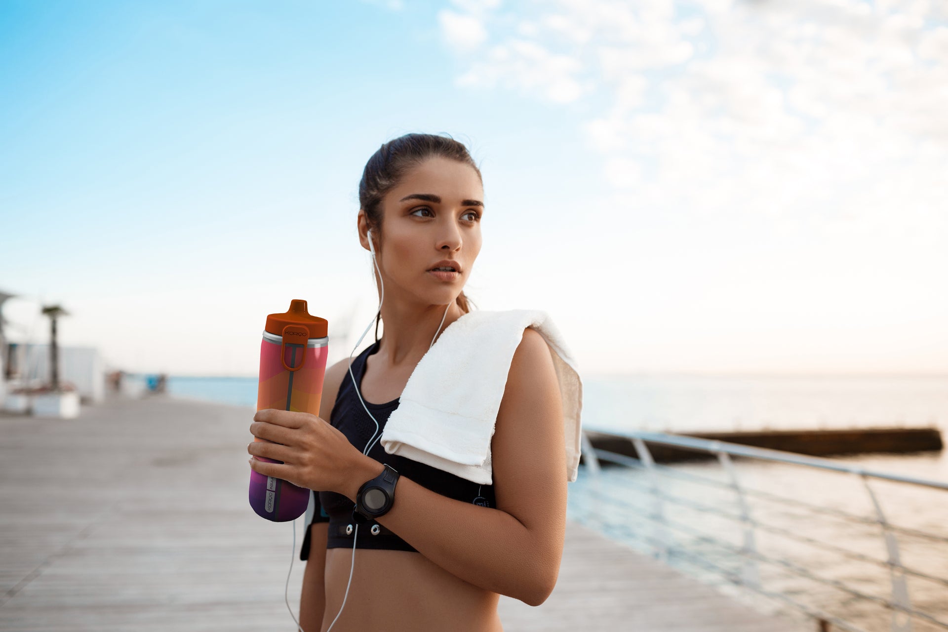 Athlete holding a KORIQO water bottle on the waterfront